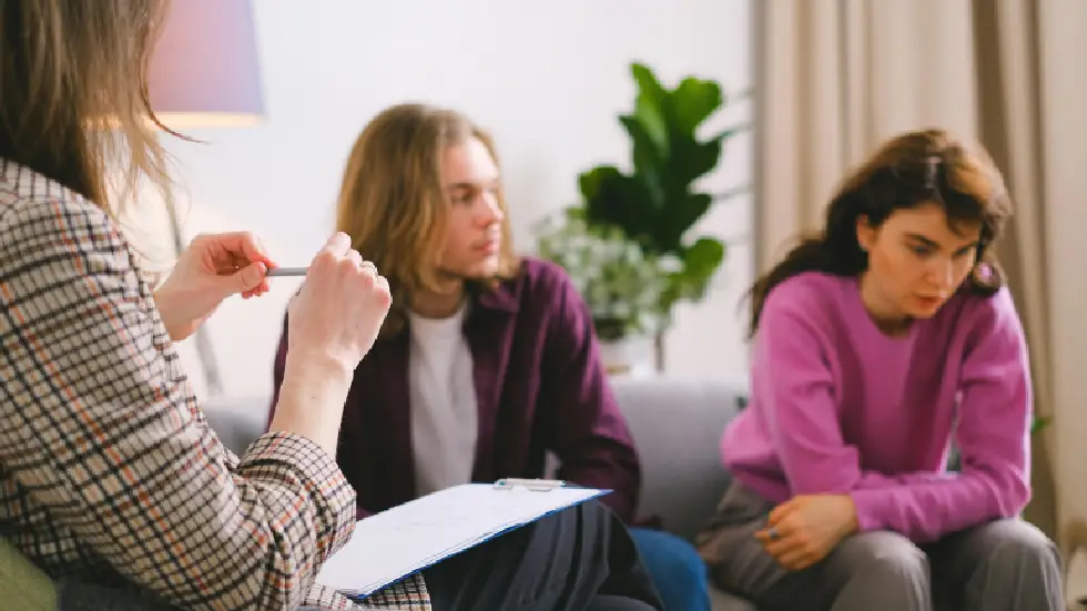 understanding failure Professional team meeting in warm natural light, supportive atmosphere with authentic expressions, collaborative workspace with laptop and notebook